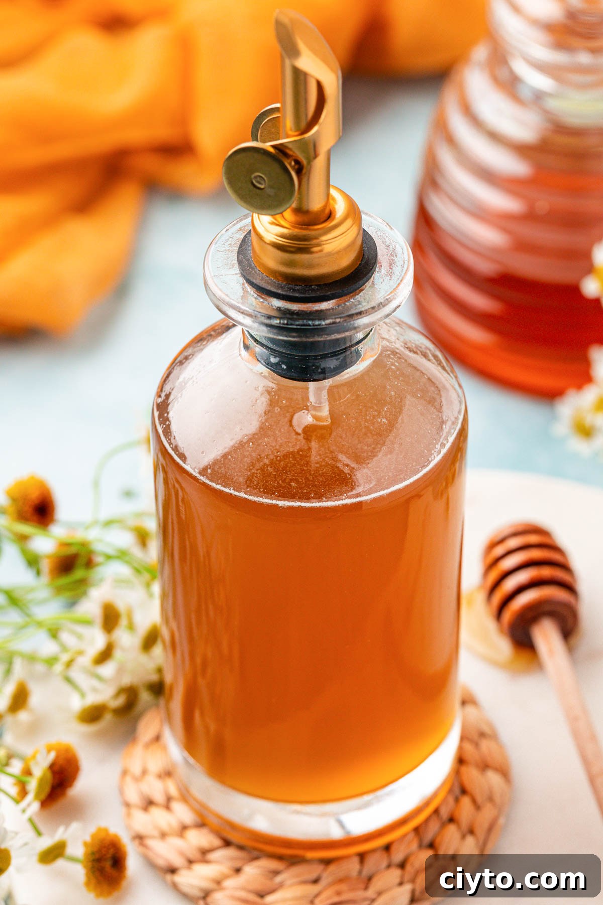A bottle of honey simple syrup on a table.