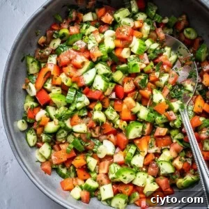 Bowl of chopped cucumbers, tomatoes, peppers and herbs.