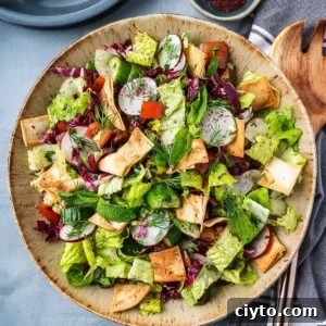 Chopped salad with lettuce, cucumbers and tomatoes in a bowl with crispy pita chips.